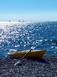 Sailboats moored on sea against blue sky