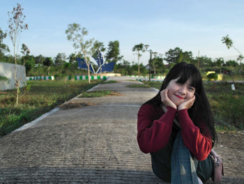 Young woman looking away while standing against trees