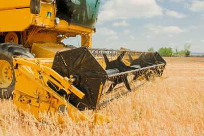 Yellow tractor plowing field and collecting close-up view of yellow tractor plowing field and collecting ears