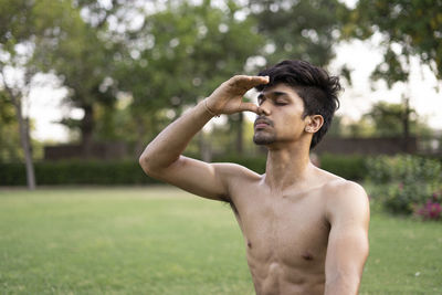 Young man looking away while standing on field