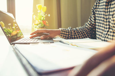 Midsection of man using laptop on table