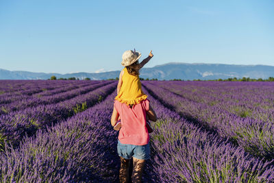 Rear view of woman walking on field against sky