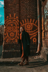 Full length of woman standing against brick wall