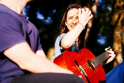 Midsection of man by woman holding guitar