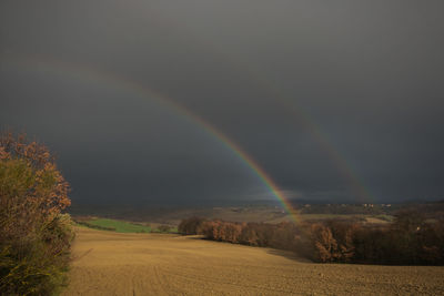 Scenic view of rainbow over landscape against sky