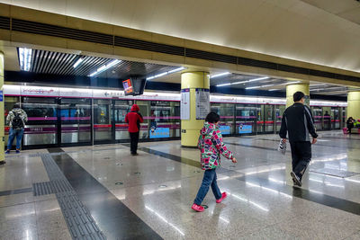 Rear view of people walking on railroad station platform