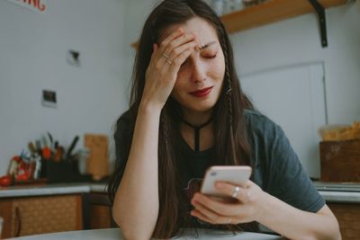 Young beautiful woman crying with the smartphone at home