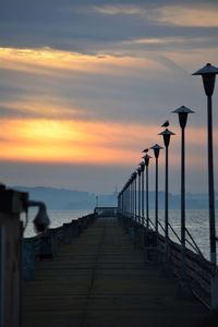 Pier over sea against sky during sunset