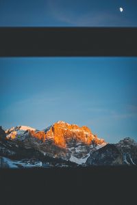 Snow covered mountain against blue sky