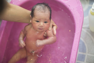 Cropped hand of mother bathing daughter in bathtub