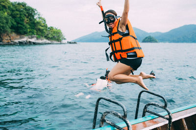 Full length portrait of woman jumping into sea