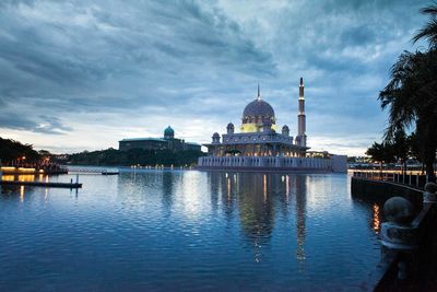 Putra mosque by lake against cloudy sky at dusk