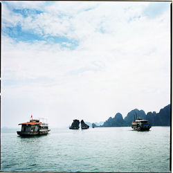 Boats sailing in sea against sky