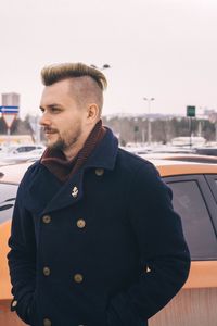 Handsome mid adult man in warm clothing looking away while standing on street against clear sky