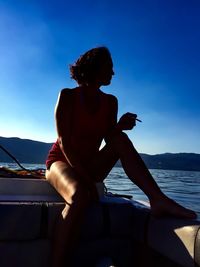 Woman sitting on boat sailing in sea against sky