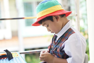 Side view of boy holding hat