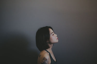 Side view of woman standing by wall