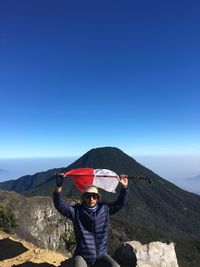 Portrait of man holding flag while standing against mountain