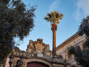 Low angle view of trees and building against sky