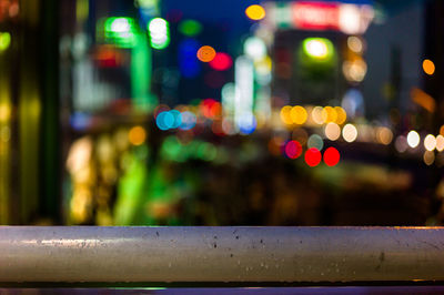 Close-up of wet illuminated railing in city at night