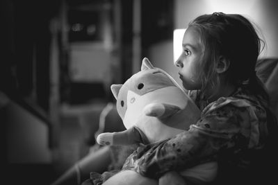 Black and white of a little girl holding stuffed animal.