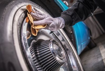 Cropped hand of person cleaning car tire