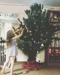 Girl decorating christmas tree at home