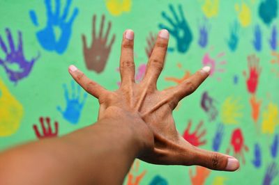 Cropped hand of person gesturing towards colorful wall