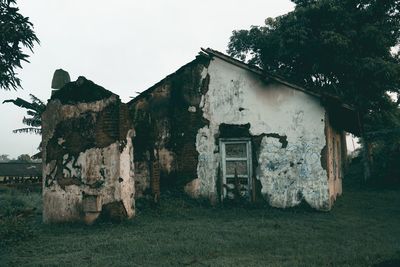 Old abandoned house on field against sky