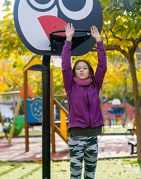 Portrait of cute girl with arms raised standing in playground