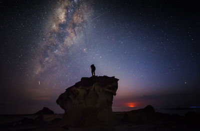 Silhouette rock formations against sky at night