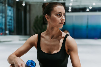 Smiling woman holding water bottle sitting at gym