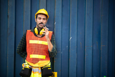 Portrait of man wearing hat standing against wall