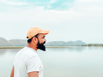 Man standing by lake against sky