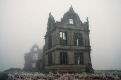 View of castle in foggy weather against sky