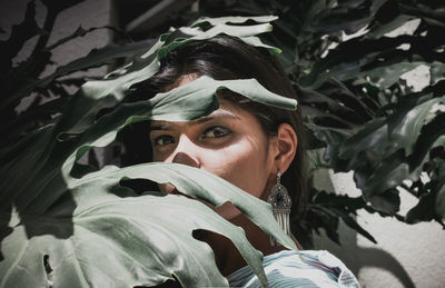 Close-up portrait of confident young woman standing amidst plants