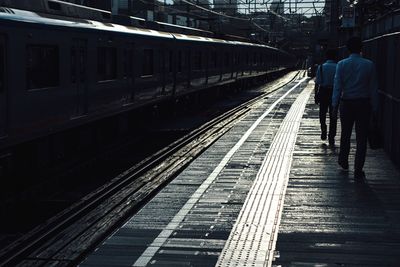Rear view of man walking on railroad station platform