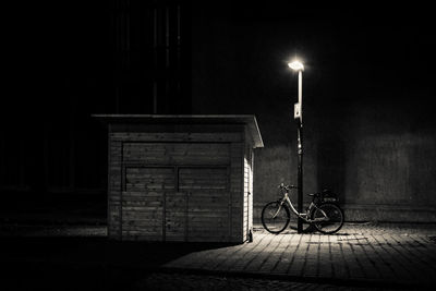 Bicycle parked on street against building at night