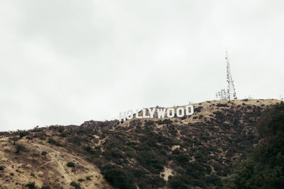 Low angle view of text on hill against sky