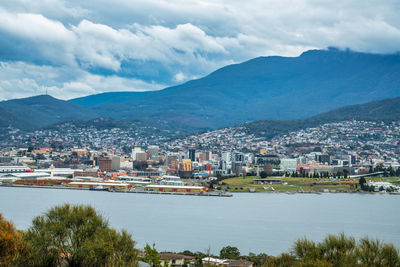 Scenic view of townscape by mountains against sky