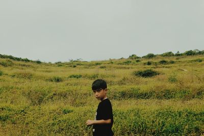Boy standing on field against clear sky