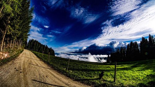 Road amidst field against sky