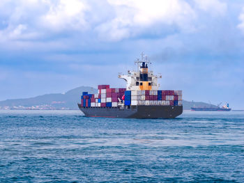 A container ship arriving to industial port on smooth sea.