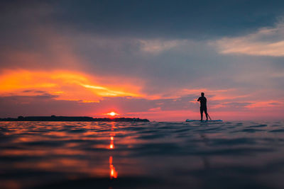 Silhouette man standing on beach against sky during sunset