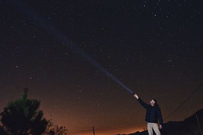 Low angle view of man standing against sky at night