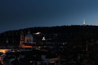 Illuminated buildings in city against clear sky at night