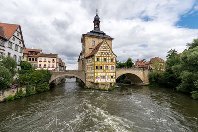 Arch bridge over river amidst buildings against sky