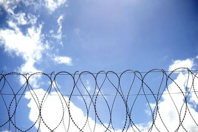 Low angle view of barbed wire fence against sky