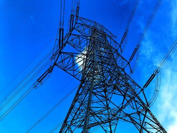 Low angle view of electricity pylon against blue sky