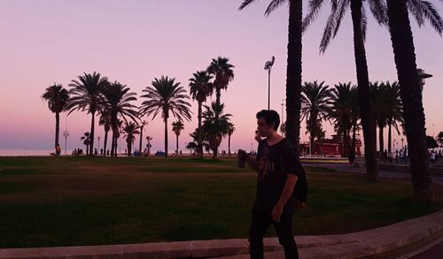 Full length of woman standing by palm tree against sky